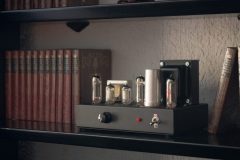 Audio tube amplifier on a small bookshelf.