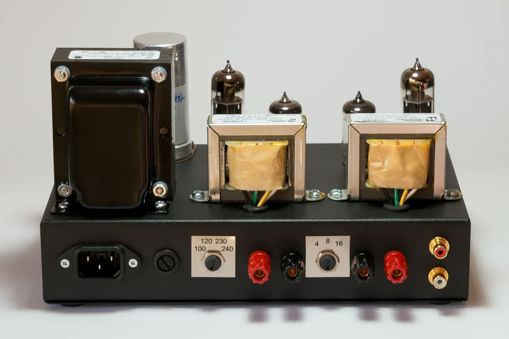 Rear view of the 1955 Gen2 amplifier showing the IEC mains inlet, voltage selector, speaker impedance selector, speakers binding posts and RCA inputs.