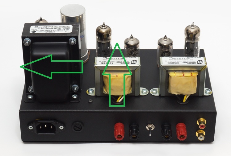 Amplifier rear view showing two output transformers and a power transformer, with markings indicating magnetic axis orientation.
